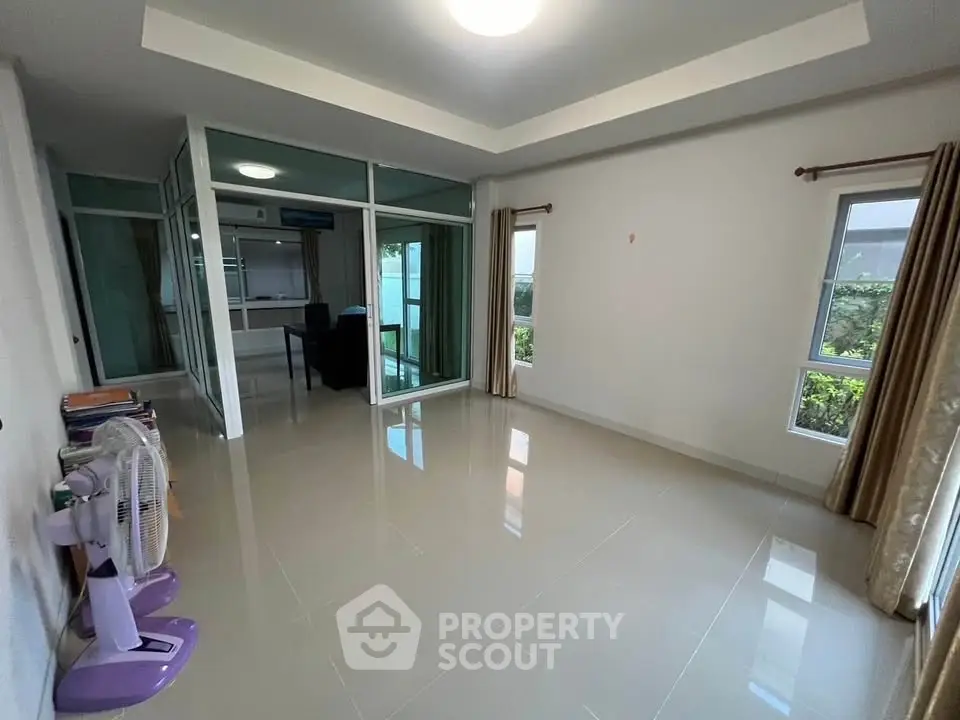 Spacious living room with large windows and glass partition, offering ample natural light and modern design.