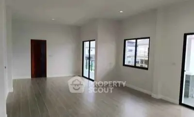 Spacious unfurnished room with large windows and wooden flooring, perfect for customization.