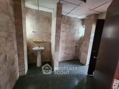 Spacious bathroom with elegant stone tiles and pedestal sink