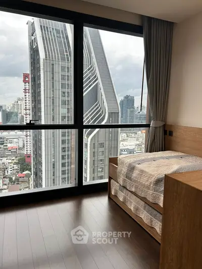 Modern bedroom with stunning city view through large windows in high-rise building.