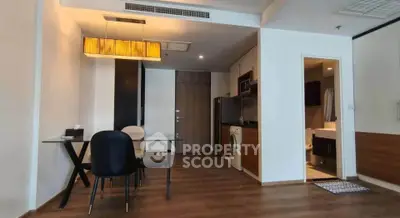 Modern apartment interior with dining area and kitchen featuring sleek design and wooden flooring.