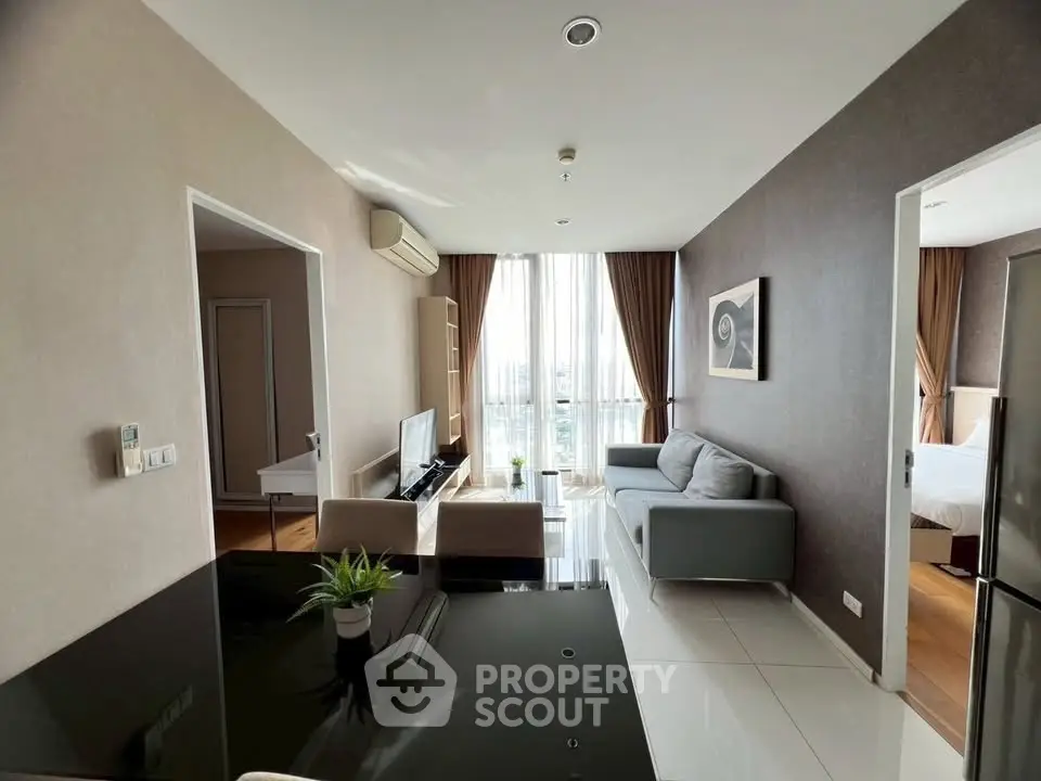 Modern living room with sleek furniture and large windows offering natural light and city views.