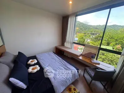 Modern bedroom with large window offering stunning mountain views, featuring cozy bed and stylish seating area.