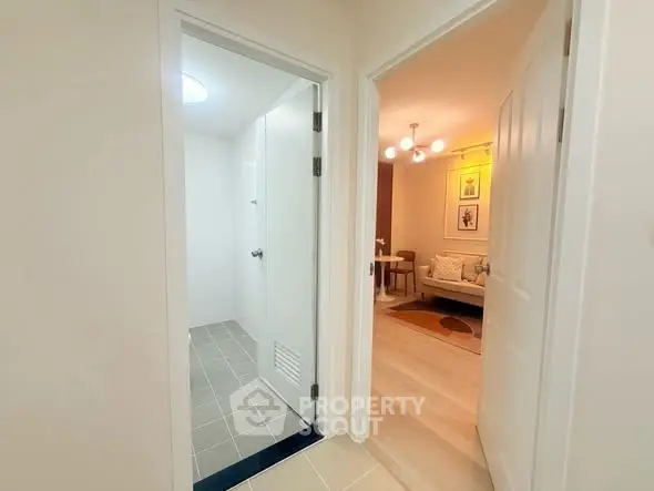 Modern apartment hallway leading to a cozy living room and a tiled bathroom.