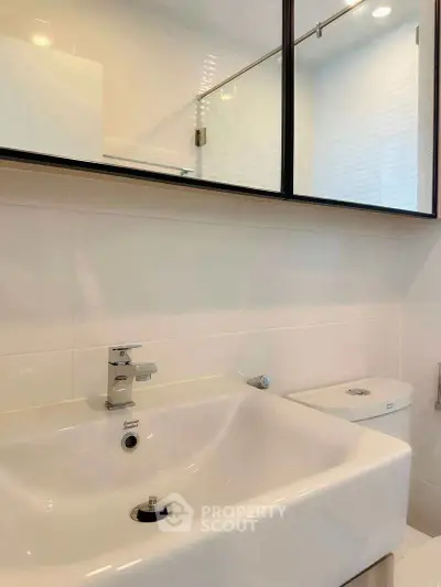 Modern bathroom with sleek sink and mirror cabinet design.