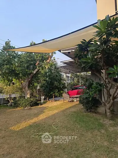 Charming suburban garden with lush greenery and modern shade sail, perfect for outdoor relaxation.
