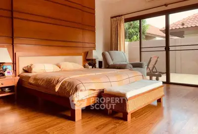 Spacious bedroom with wooden flooring and large sliding glass doors opening to a patio.