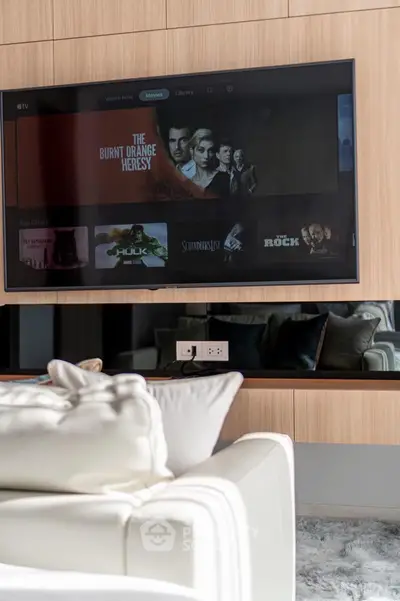 Modern living room with wall-mounted TV and plush white sofa, perfect for entertainment and relaxation.