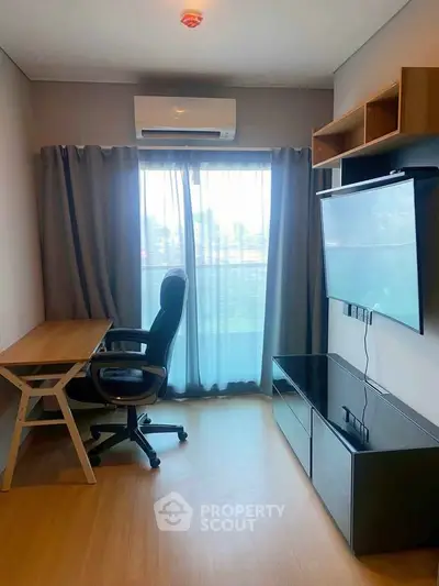 Modern study room with desk, chair, and wall-mounted TV in a bright apartment.
