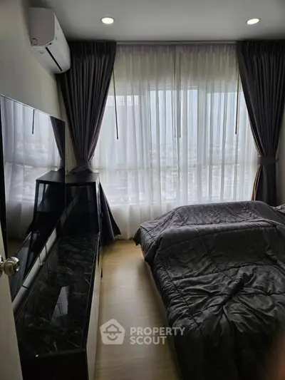 Modern bedroom with large window and city view, featuring sleek furniture and stylish decor.