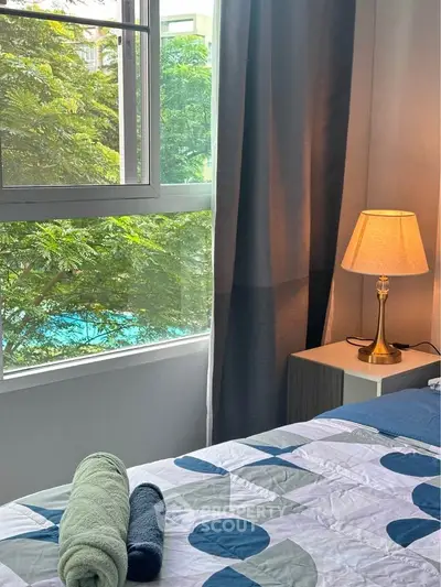Cozy bedroom with a view of lush greenery and pool, featuring modern decor and soft lighting.