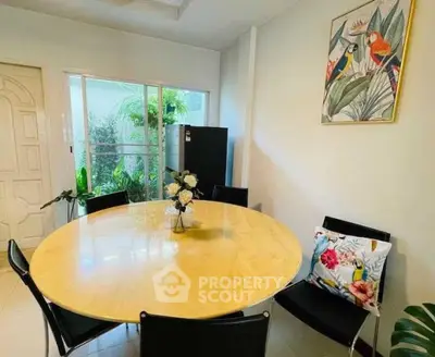 Charming dining area with round table and garden view, perfect for cozy meals.