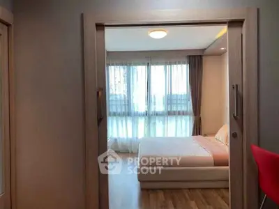 Cozy bedroom with large window and wooden flooring, perfect for relaxation and comfort.