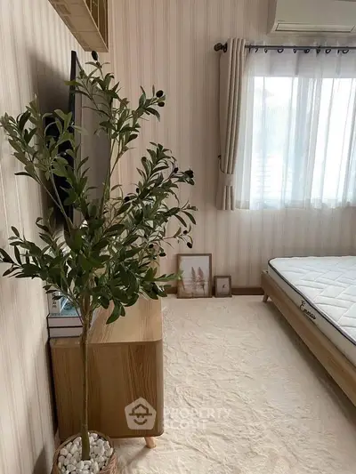 Cozy bedroom with natural light, minimalist decor, and a potted plant enhancing tranquility.