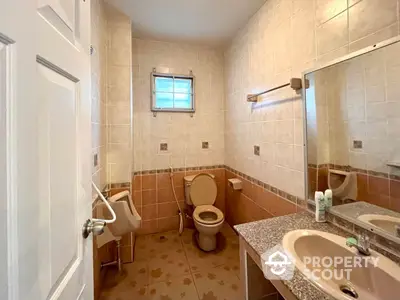 Spacious bathroom with beige tiles, large mirror, and accessible features including grab bars and a wide door.