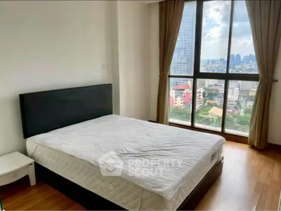 Spacious bedroom with large window offering stunning city views in modern apartment.
