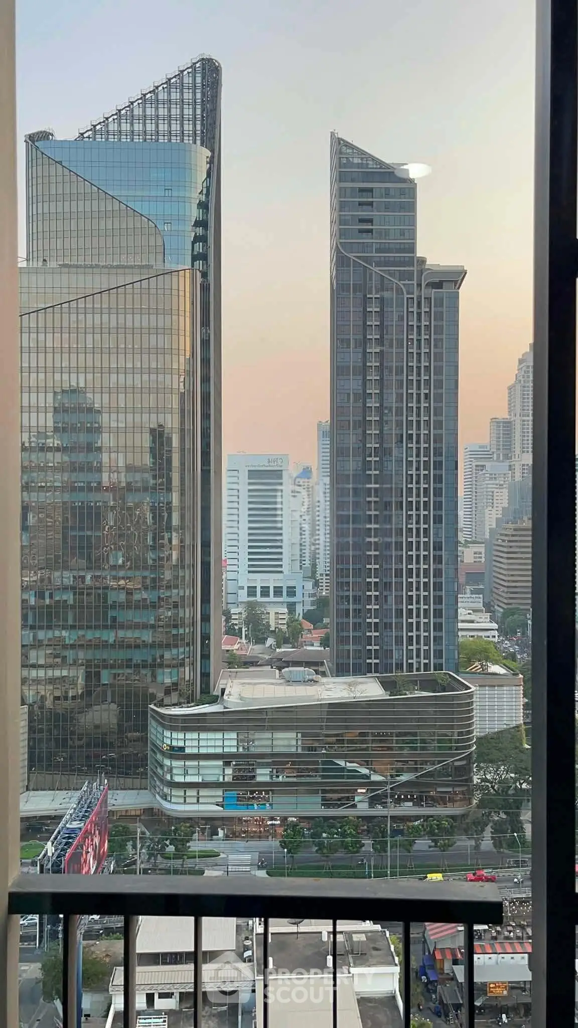 Stunning cityscape view from a high-rise balcony showcasing modern skyscrapers at sunset.