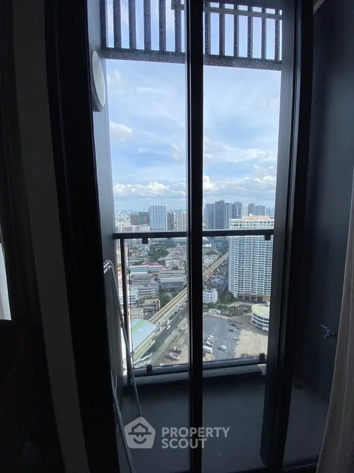 Stunning cityscape view from a high-rise balcony, showcasing urban skyline and clear skies.