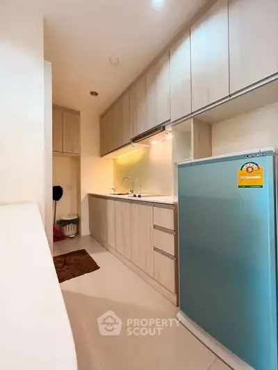 Modern kitchen with sleek cabinetry and compact fridge in a cozy apartment.