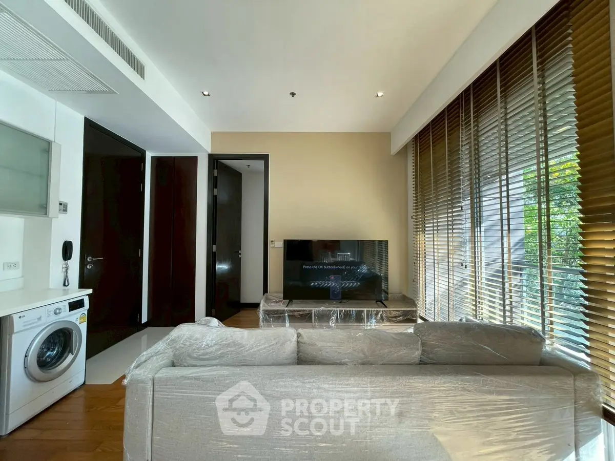 Modern living room with natural light, featuring a washing machine and sleek furnishings.
