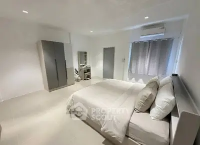 Spacious modern bedroom with minimalist decor and ample natural light.