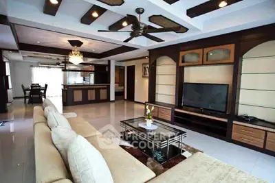 Spacious living room with modern decor and open kitchen layout, featuring elegant ceiling design and cozy seating.