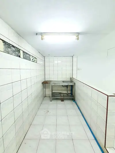 Minimalist kitchen space with tiled walls and basic sink setup