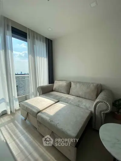 Bright living room with plush sofa and city view through large window, perfect for relaxation.