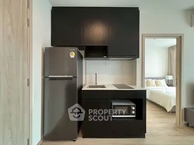 Modern compact kitchen with sleek black cabinets and stainless steel appliances