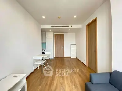 Spacious modern living room with wooden flooring and minimalist furniture in a bright apartment.