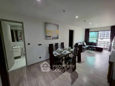 Modern open-plan living and dining area with city view and sleek furnishings.