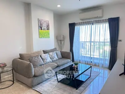 Modern living room with plush sofa, glass coffee table, and balcony view in a stylish apartment.
