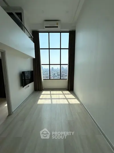 Spacious modern room with large windows offering stunning city views.