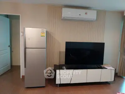 Modern living room with sleek TV unit and air conditioning, featuring a stylish fridge for convenience.
