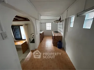 Spacious kitchen with open layout and gas stove, featuring tiled flooring and ample natural light.
