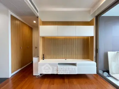 Modern minimalist living room with wooden accents and sleek white cabinetry.