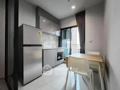 Modern kitchen with sleek design, featuring a fridge, dining table, and open balcony view.