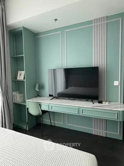 Modern bedroom with stylish TV setup and elegant green wall paneling