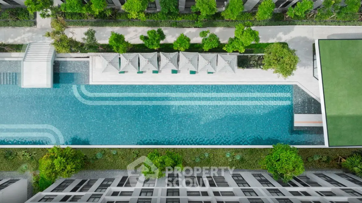 Stunning aerial view of modern apartment complex with luxurious swimming pool and lush greenery.
