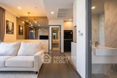 Modern living room with elegant decor and open layout, featuring a cozy sofa and stylish lighting.