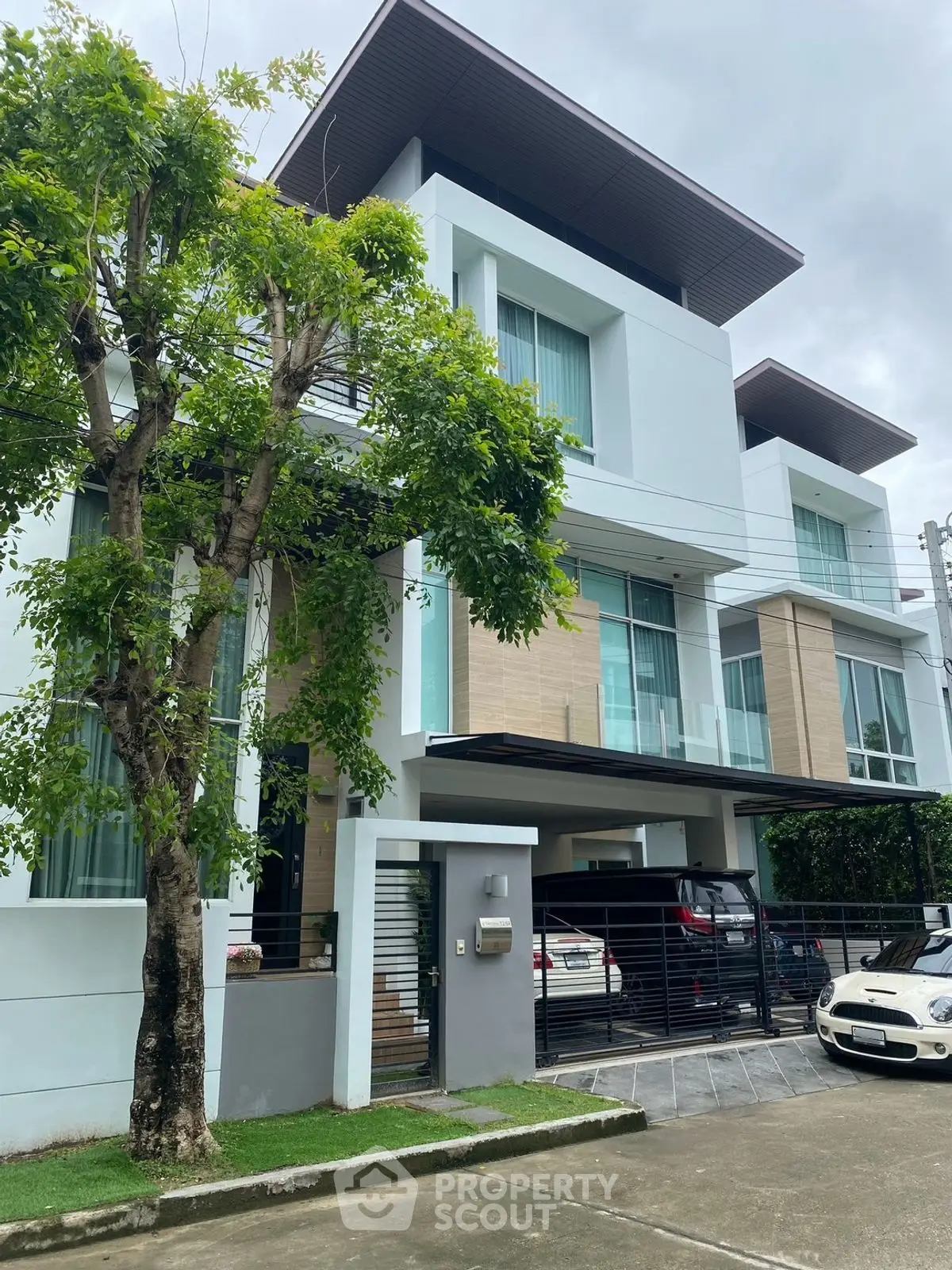 Modern three-story building with sleek design and spacious parking area.