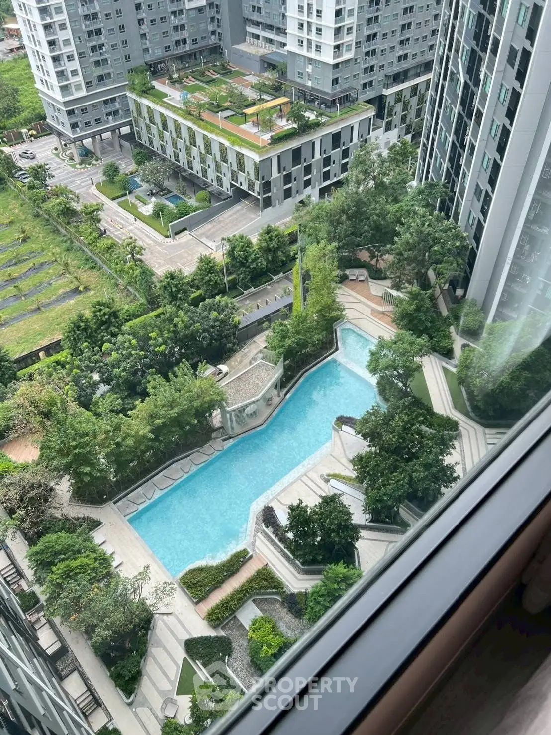 Stunning aerial view of modern residential complex with pool and lush greenery.