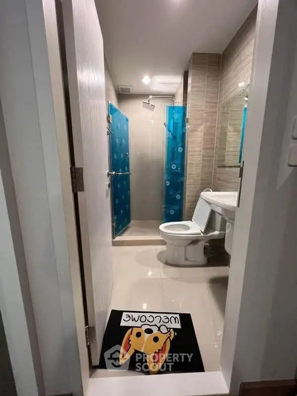 Modern bathroom with shower and toilet, featuring a playful welcome mat.