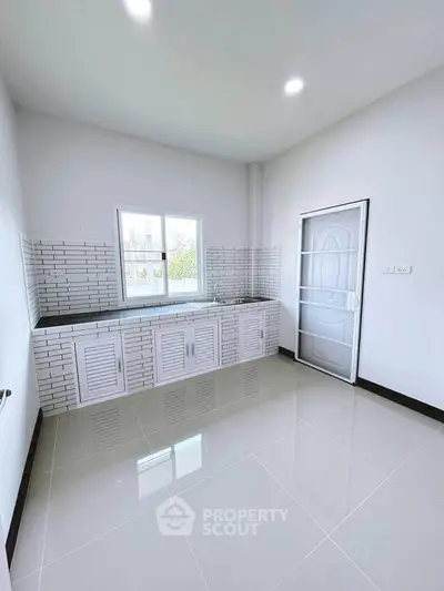 Spacious modern kitchen with sleek white cabinetry and tiled backsplash