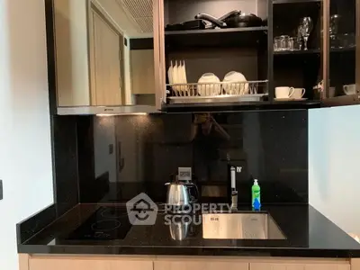 Modern kitchen with sleek black countertops and built-in appliances, featuring an electric stove and stylish cabinetry.