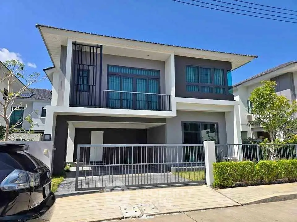 Modern two-story house with sleek design and spacious driveway in a suburban neighborhood.