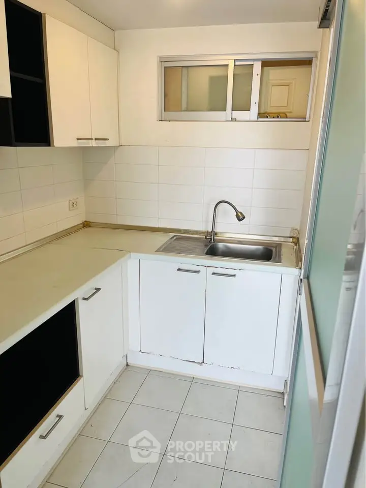 Compact kitchen with white cabinets and tiled backsplash, featuring a stainless steel sink and modern faucet.