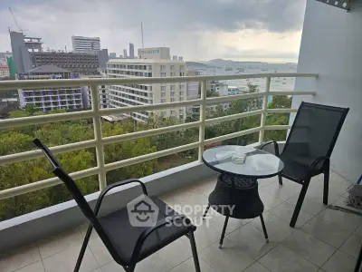 Stunning balcony view with modern seating overlooking cityscape and ocean horizon.