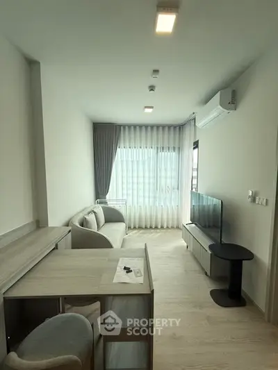 Modern living room with sleek furniture and large window, perfect for cozy gatherings.