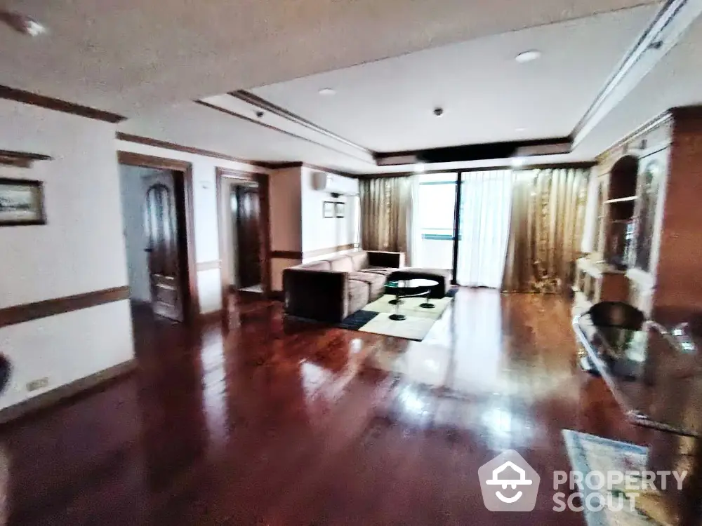 Spacious living room with wooden flooring and elegant furnishings in a luxury apartment.